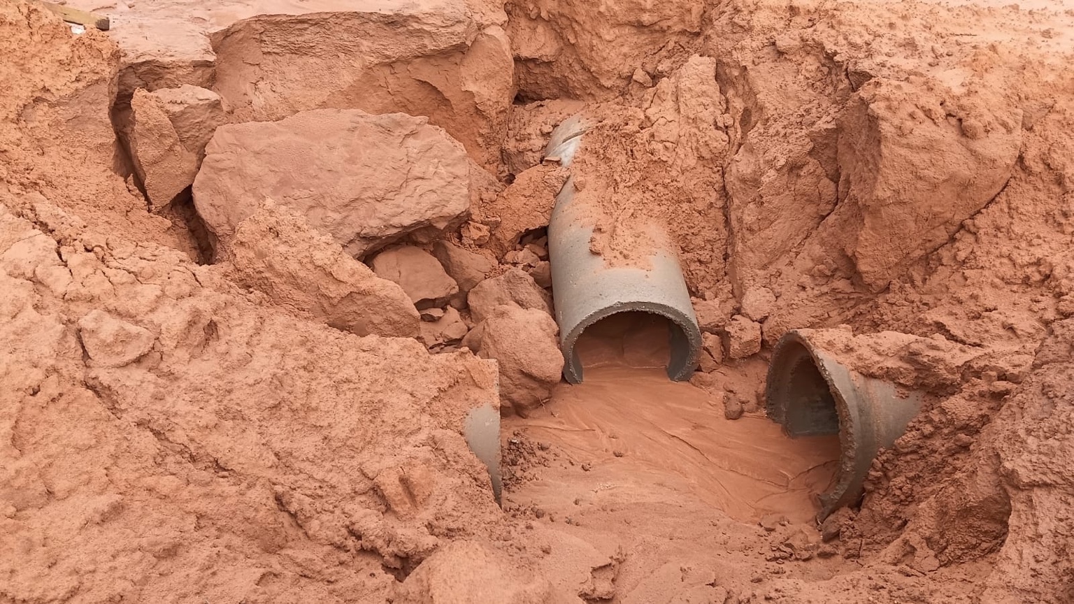 Trecho da rede de drenagem do Villa Bella com solo deslocado e água acumulada